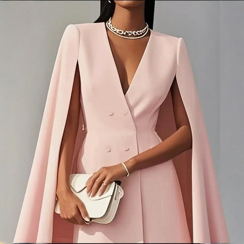 Woman wearing a pink cape over a formal dress against a gray background