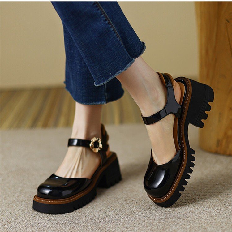 Black platform shoes with brown soles worn by a person in jeans.