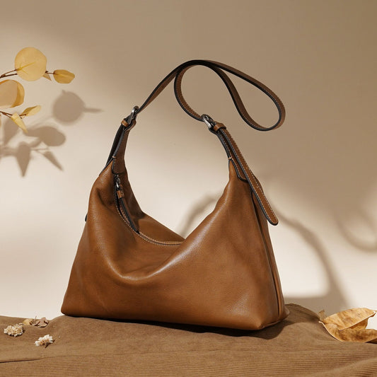 Brown leather handbag on a textured surface with a neutral background