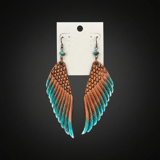 Pair of feather-shaped earrings with brown and teal gradient on a wooden background
