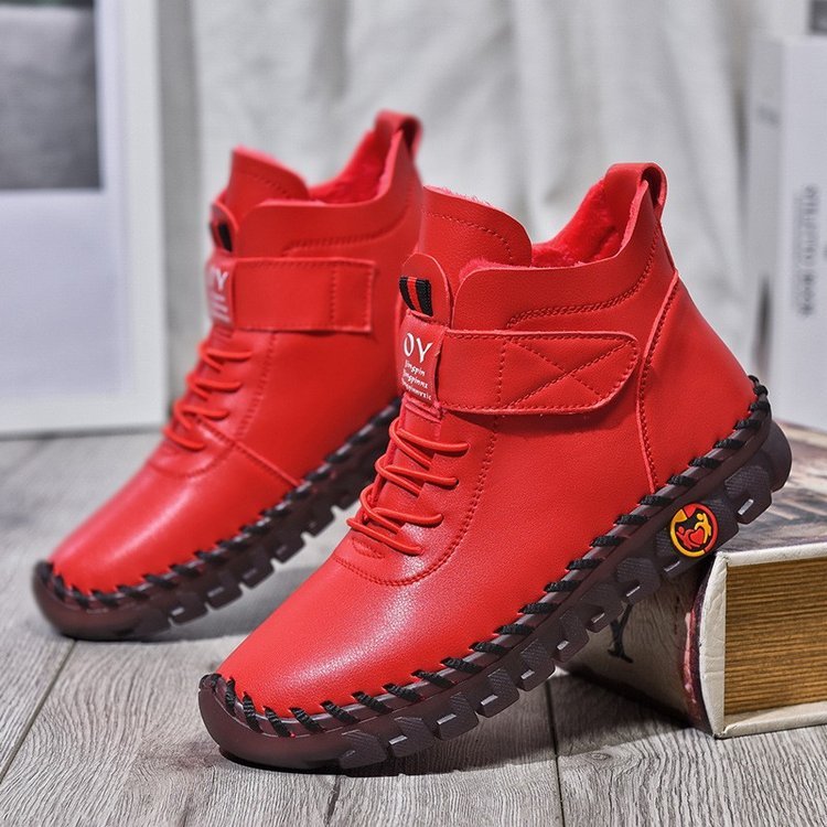 Red high-top boots with black soles on a wooden floor.