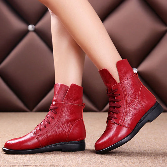 Red leather boots worn by a person on a brown textured background