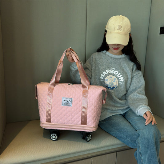 Person holding a pink quilted duffel bag with a neutral background
