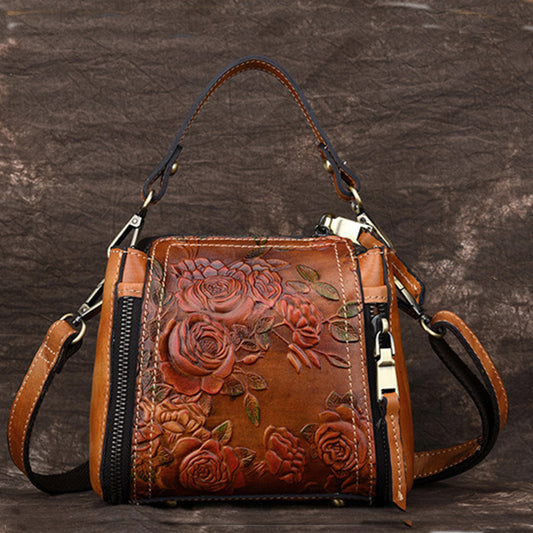 Brown leather handbag with floral embossing on a dark background