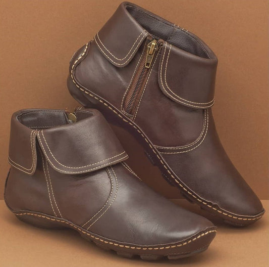 Pair of brown leather boots with zippers on a brown background