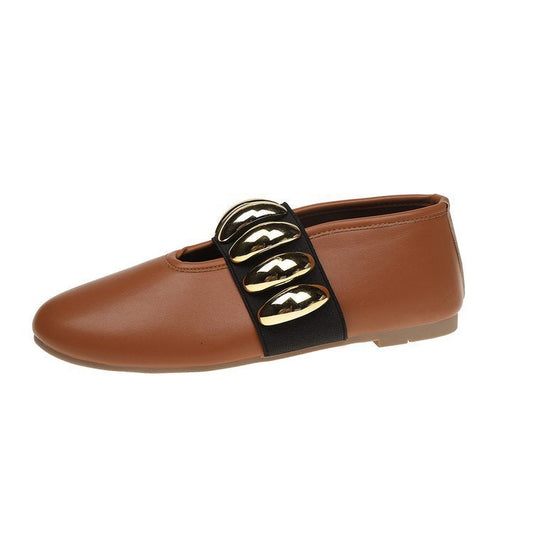 Brown flat shoe with gold and black strap on a white background
