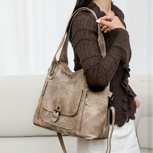 Person holding a beige handbag with a neutral background