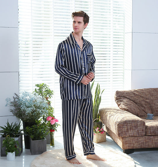 Man wearing striped pajamas standing in a modern living room with plants and a sofa.