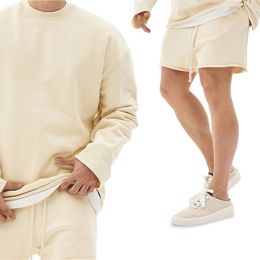 Two people wearing matching beige outfits with shorts on a white background
