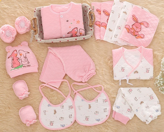 Collection of pink baby clothes and accessories on a wooden surface