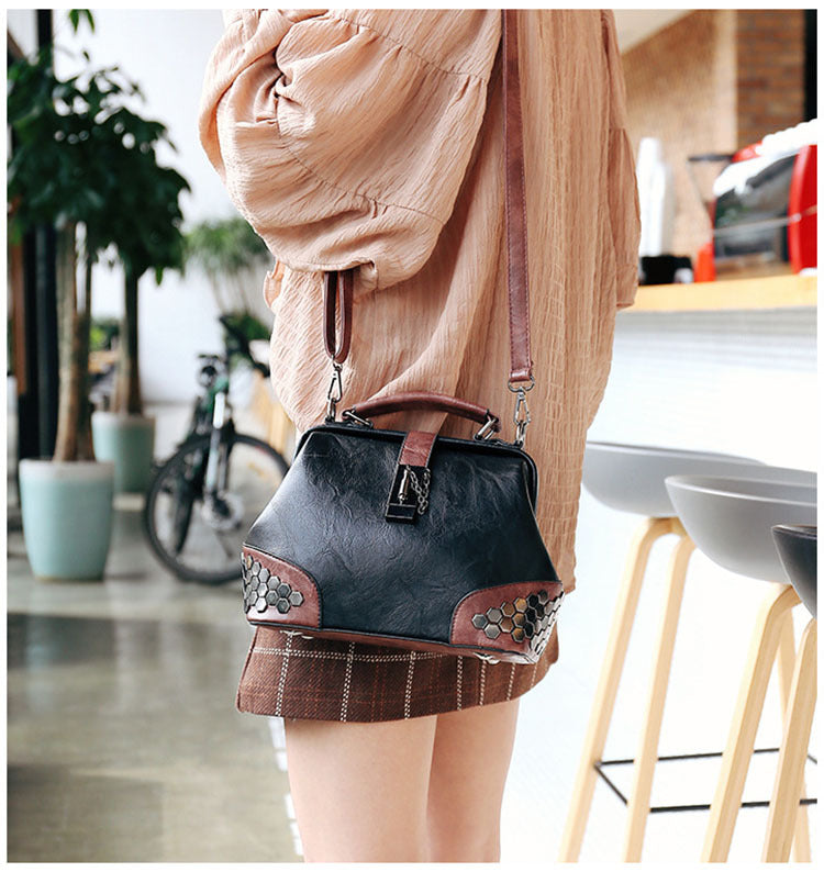 Person wearing a black handbag with decorative elements in an indoor setting