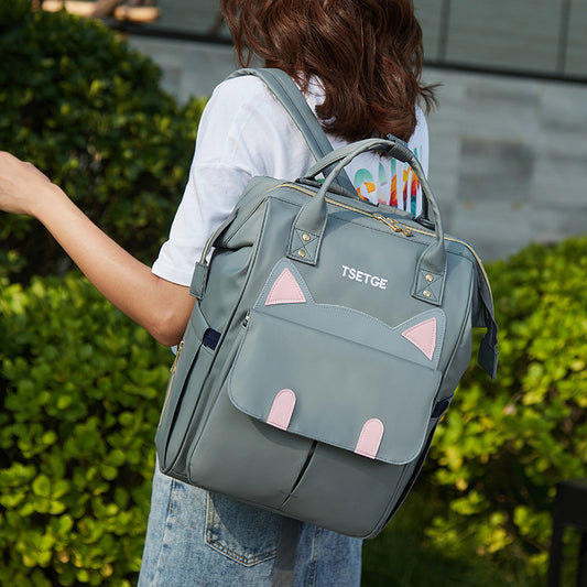 Person wearing a gray backpack with cat ears and pink accents, standing outdoors.