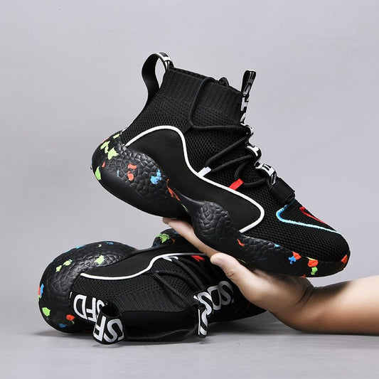 Black high-top sneakers with colorful accents held by a hand on a gray background
