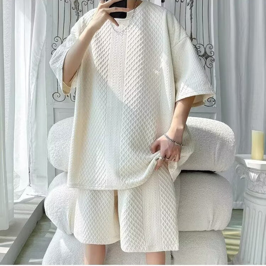 Person wearing a textured white outfit sitting on a couch in a bright room.