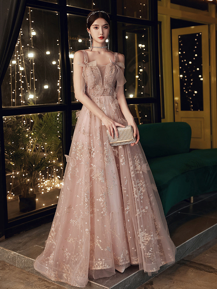 Woman in a pink lace dress holding a clutch in an indoor setting with decorative lights.