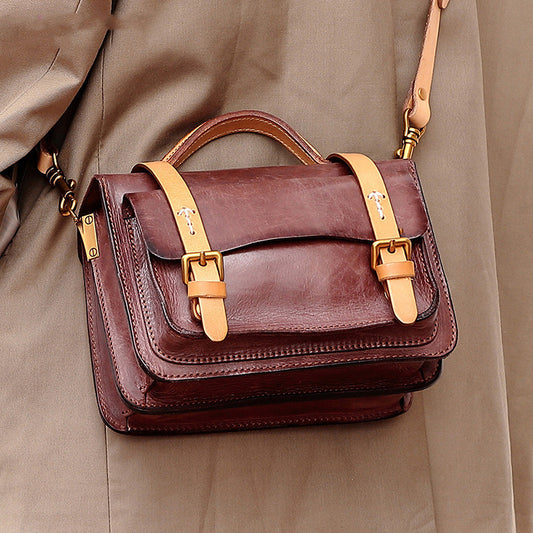 Brown leather handbag with gold accents on a beige background