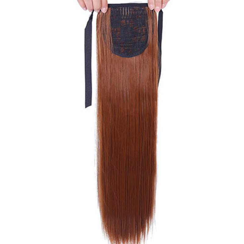 Brown hair extension held by a hand on a white background