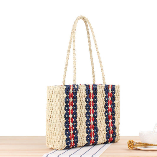 Woven handbag with red, white, and blue stripes on a wooden surface.