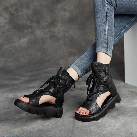 Black lace-up sandals worn with blue jeans on a gray background