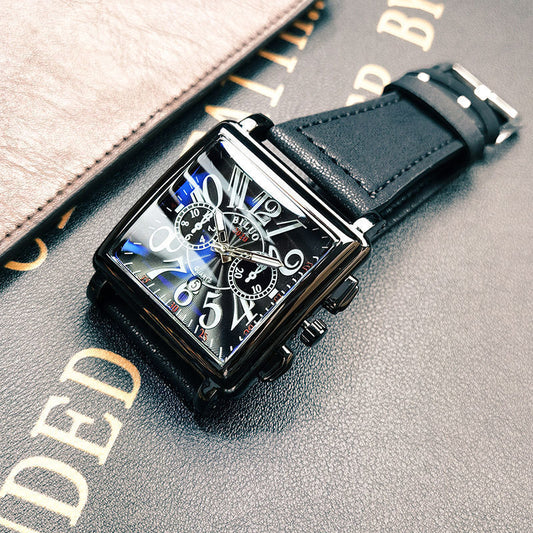 Black rectangular watch with detailed face on a textured surface