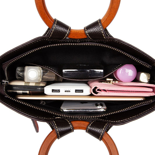 Open black handbag with various items including a phone, wallet, and pink object on a white background