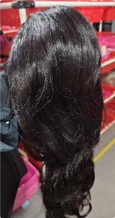 Braided hair extension held by a person with a red chair and pink bag in the background