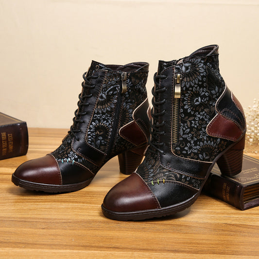 Pair of black and brown floral-patterned ankle boots on a wooden surface.