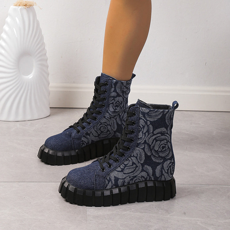 Blue floral-patterned boots with black soles on a light wooden floor.