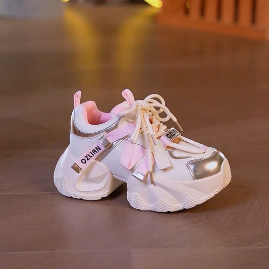 White and pink children's sneakers on a wooden floor