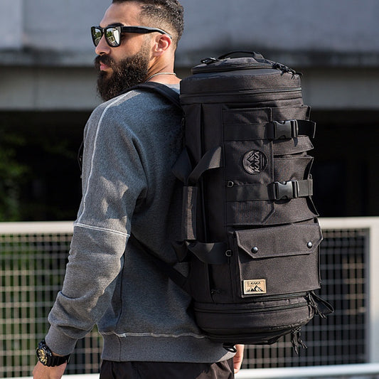 Man wearing a large black backpack with a visible brand logo, standing outdoors.
