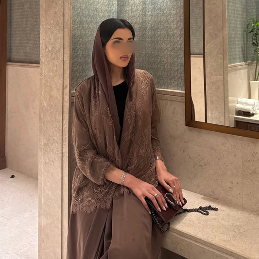 Woman in a brown outfit sitting on a ledge in a bathroom.