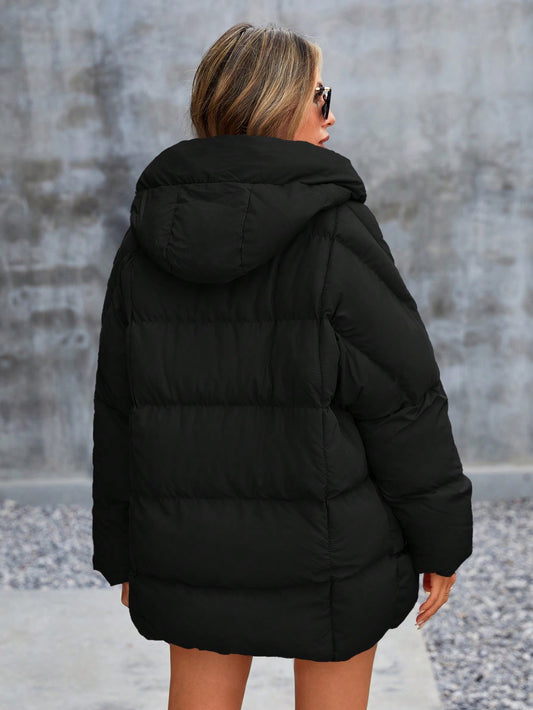 Person wearing a black puffer jacket with a neutral background