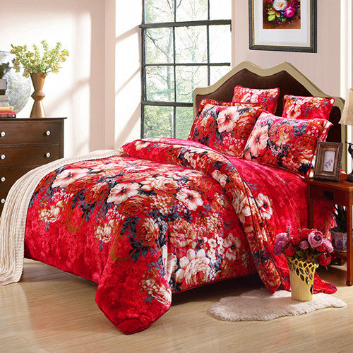 Red floral bedding set on a bed in a bedroom with decor elements.