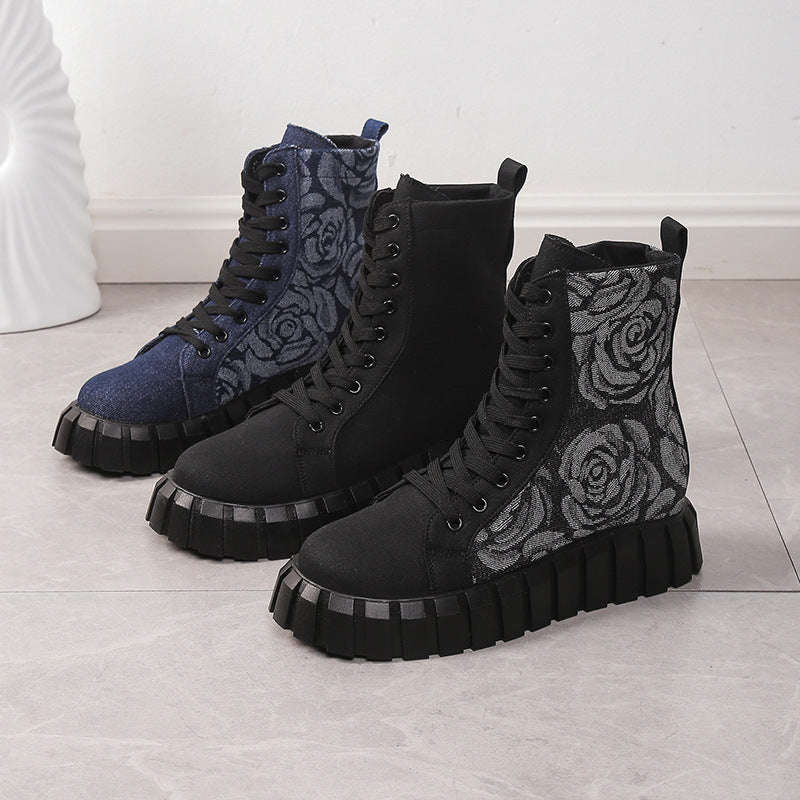 Pair of black and blue boots with floral pattern on a light wooden floor.