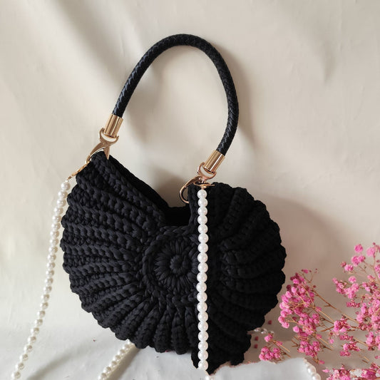 Black woven handbag with pearl strap on a beige background