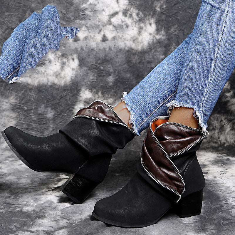Black and brown ankle boots worn with blue jeans on a textured gray background