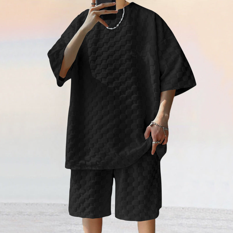Person wearing a black textured outfit with a plain background