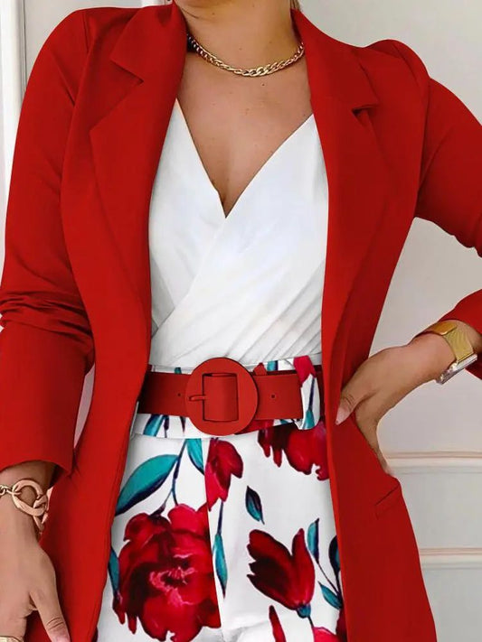 Person wearing a red blazer over a white dress with floral patterns.