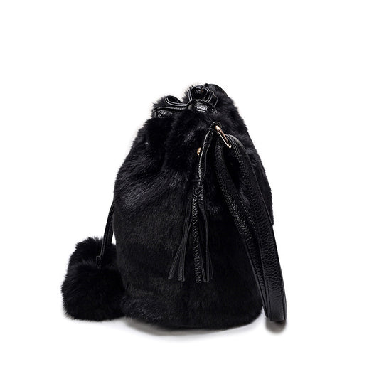 Black fur backpack with pom-poms on a white background
