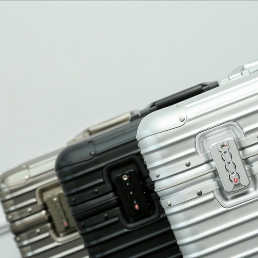 Two metallic suitcases with a visible brand logo on a light gray background