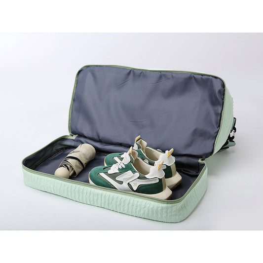 Green travel shoe organizer with shoes and an umbrella inside on a white background