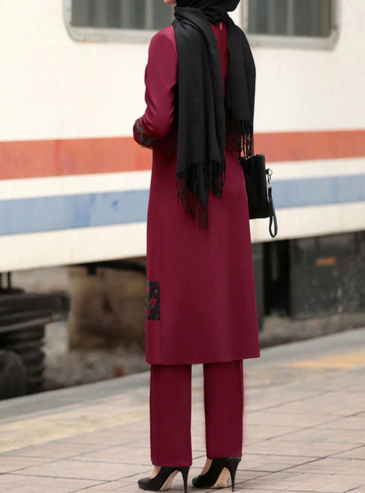 Person wearing a maroon outfit with a black scarf at a train station.