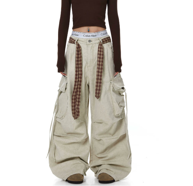 Person wearing beige wide-leg pants with plaid accents on a white background