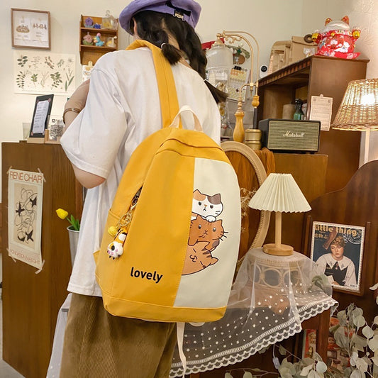 Person wearing a yellow backpack with cat designs in a room setting.