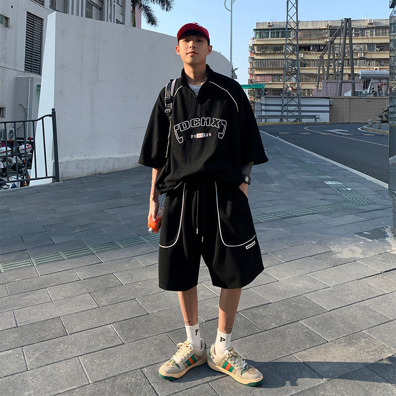 Person wearing a black outfit with visible branding on a paved street.