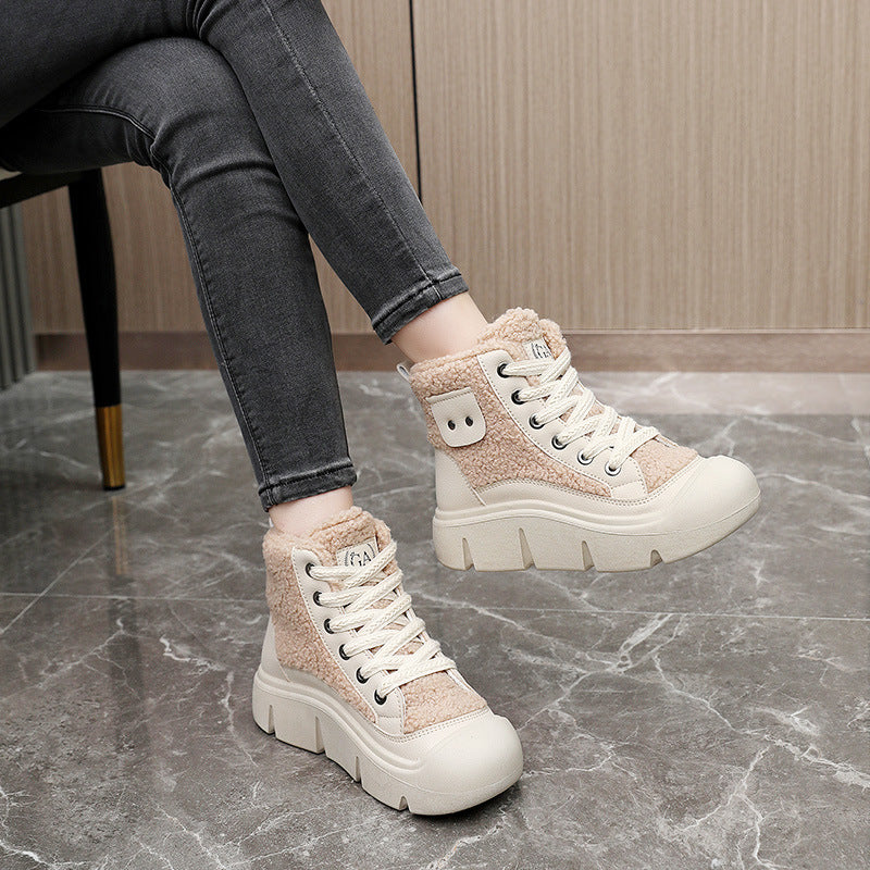 Person wearing beige high-top sneakers with white soles on a marble floor.