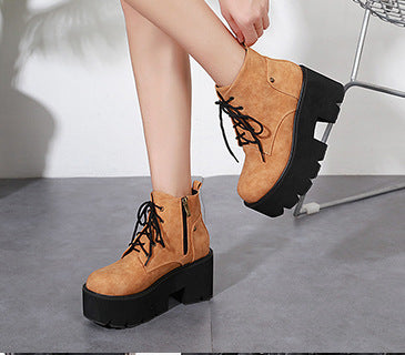 Brown platform boots being worn on a gray floor with a white background