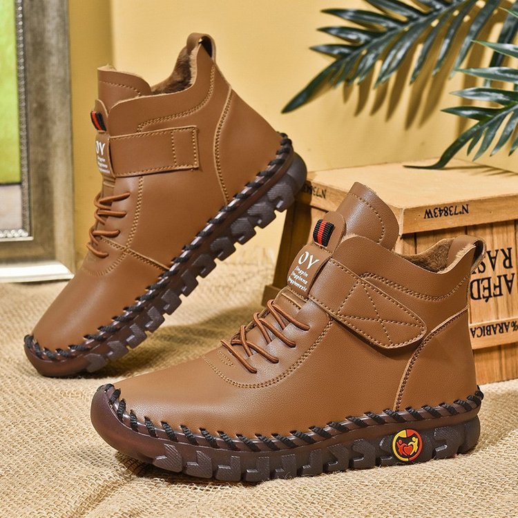Pair of brown leather boots with black soles on a textured surface.