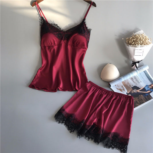 Red satin nightgown with black lace trim on a white surface.