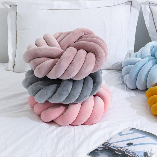 Knotted cushion in various colors on a bed